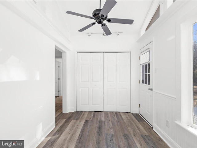 unfurnished bedroom featuring a closet, track lighting, dark hardwood / wood-style floors, and ceiling fan