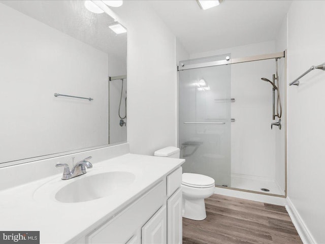 bathroom with hardwood / wood-style flooring, walk in shower, vanity, and toilet