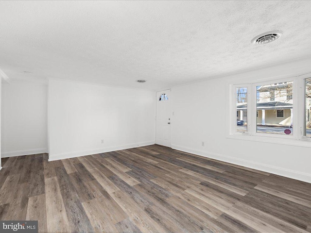 empty room with dark hardwood / wood-style flooring and a textured ceiling
