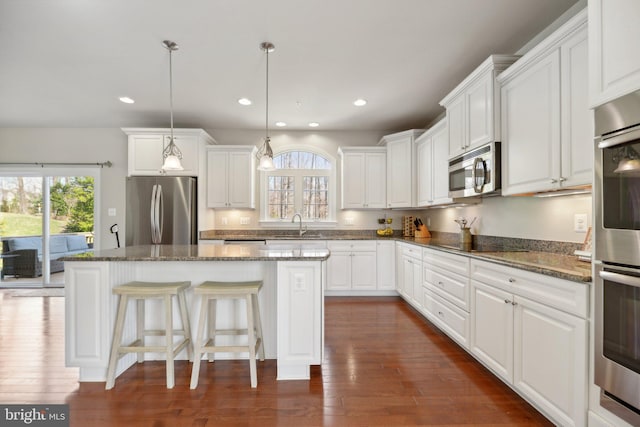 kitchen with a sink, a wealth of natural light, appliances with stainless steel finishes, and a center island