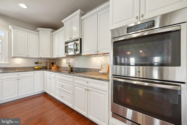 kitchen featuring dark stone countertops, dark wood finished floors, white cabinetry, recessed lighting, and stainless steel appliances