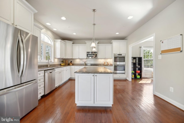 kitchen featuring dark wood finished floors, a kitchen island, white cabinetry, and stainless steel appliances