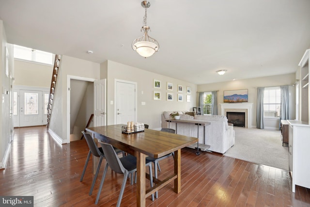 dining room featuring baseboards, a fireplace, and dark wood-style flooring