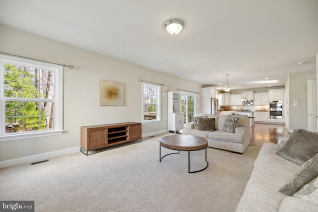 living area featuring recessed lighting, visible vents, baseboards, and light carpet