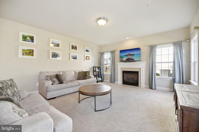 living room with a wealth of natural light, a fireplace with flush hearth, light colored carpet, and baseboards