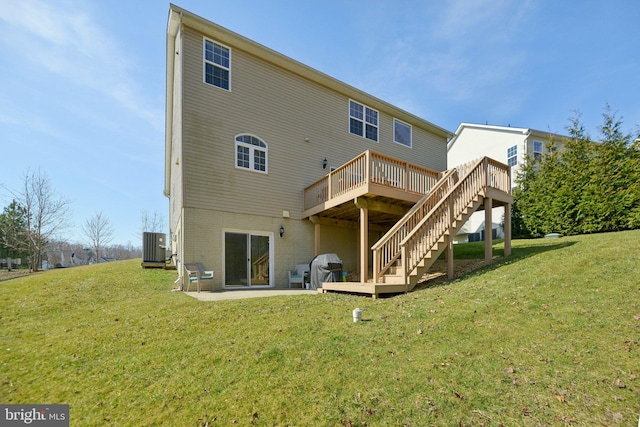 back of house with brick siding, central air condition unit, stairs, a lawn, and a deck