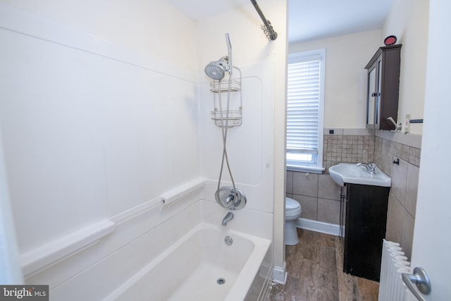 full bathroom featuring toilet, shower / bath combination, vanity, tile walls, and radiator heating unit