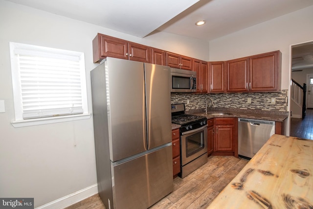 kitchen featuring appliances with stainless steel finishes, a sink, butcher block counters, and tasteful backsplash