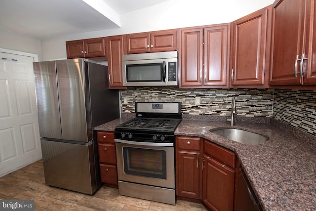 kitchen featuring tasteful backsplash, dark stone countertops, stainless steel appliances, and a sink