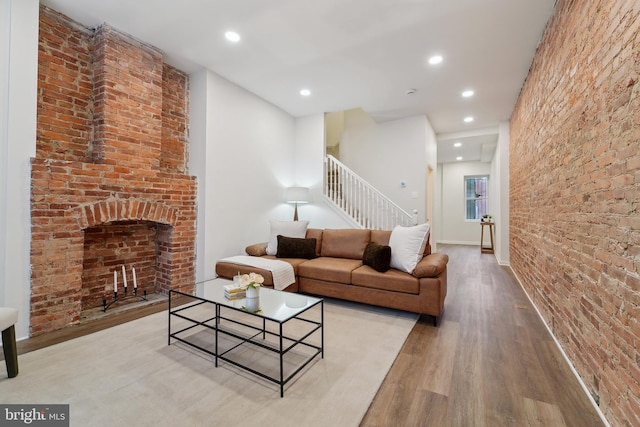 living room with brick wall, a brick fireplace, and light hardwood / wood-style flooring