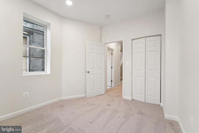 unfurnished bedroom featuring light colored carpet and a closet