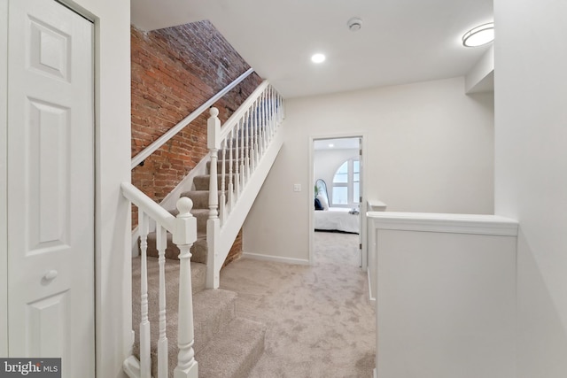 staircase with carpet floors and brick wall