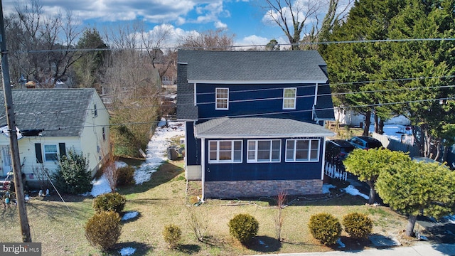 traditional-style house with a front lawn and roof with shingles