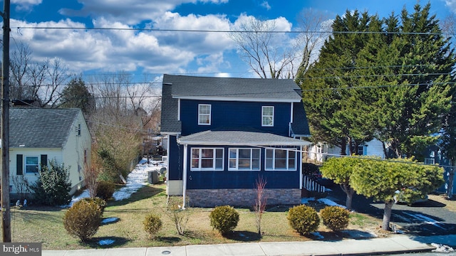 traditional home with a front yard and roof with shingles