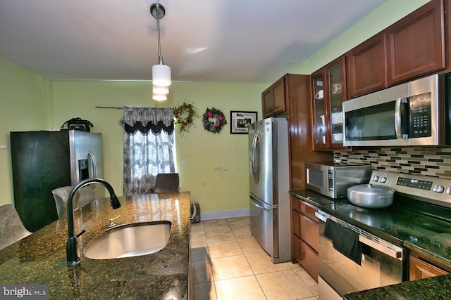 kitchen featuring decorative light fixtures, stainless steel appliances, a sink, tasteful backsplash, and glass insert cabinets