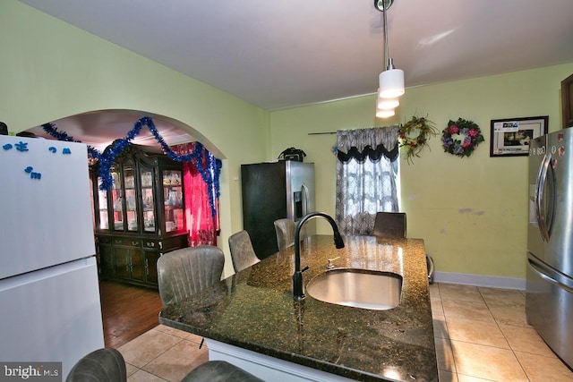 kitchen featuring light tile patterned floors, stainless steel fridge, a sink, and freestanding refrigerator