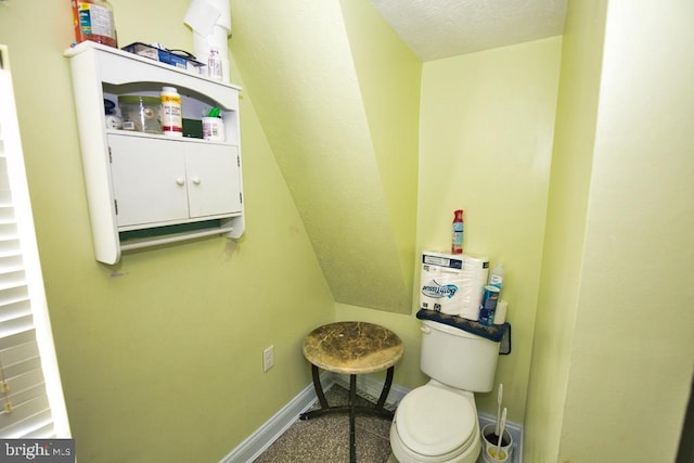 bathroom with a textured ceiling, toilet, and baseboards