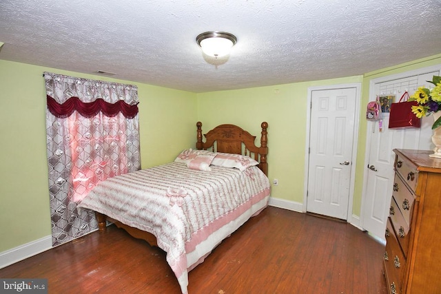 bedroom with visible vents, a textured ceiling, baseboards, and dark wood-type flooring