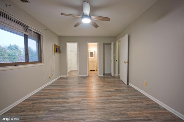 unfurnished bedroom with ceiling fan, ensuite bath, a wall mounted air conditioner, and dark hardwood / wood-style flooring