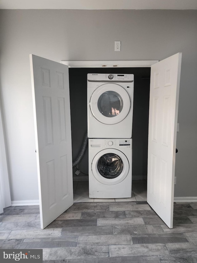 laundry room featuring stacked washer / drying machine and dark hardwood / wood-style floors