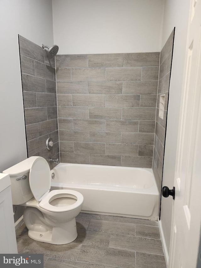 full bathroom with tiled shower / bath, vanity, and toilet