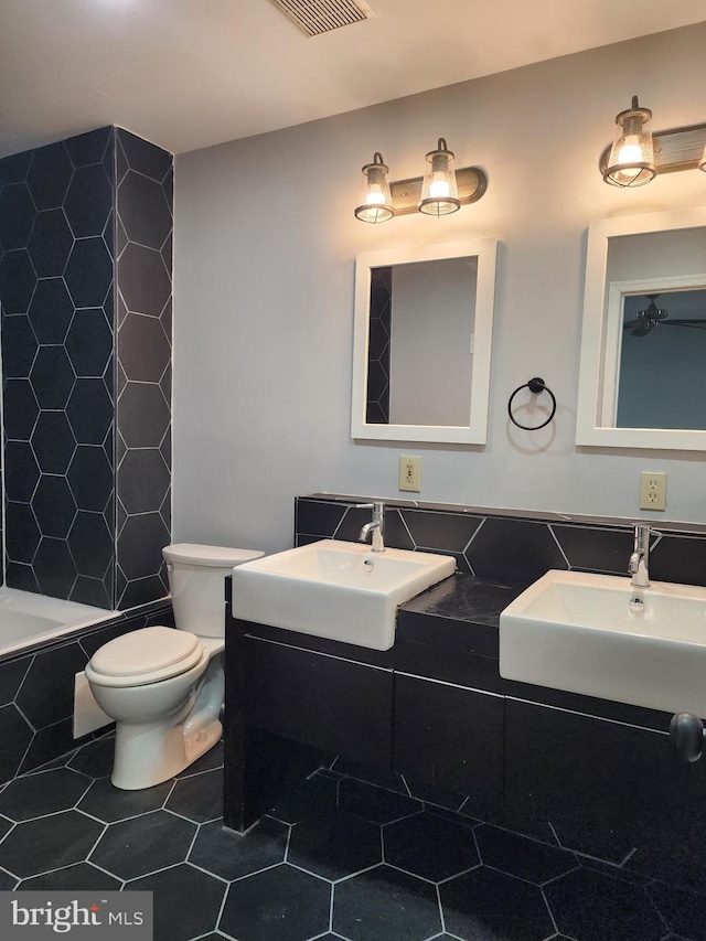 bathroom featuring tile patterned floors, toilet, vanity, and tiled tub