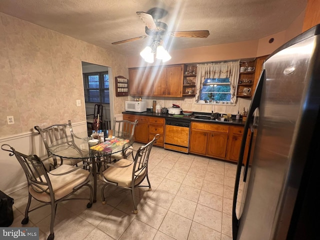 kitchen with sink, a textured ceiling, stainless steel refrigerator, dishwashing machine, and ceiling fan