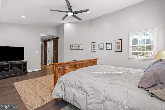 bedroom featuring ceiling fan, a barn door, and dark hardwood / wood-style flooring