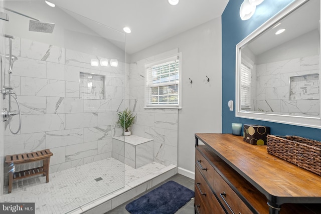 bathroom with lofted ceiling, vanity, and a tile shower