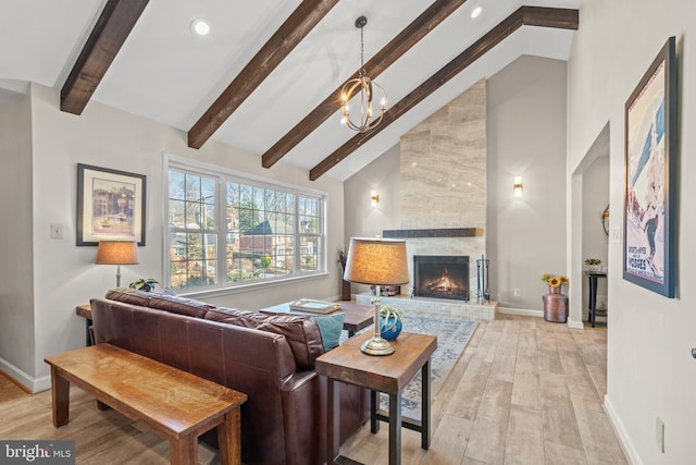 living room with beam ceiling, a chandelier, high vaulted ceiling, light wood-type flooring, and a fireplace