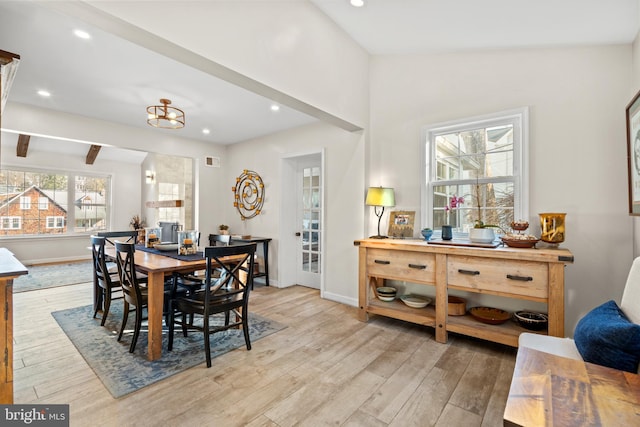 dining space featuring light hardwood / wood-style flooring and vaulted ceiling with beams