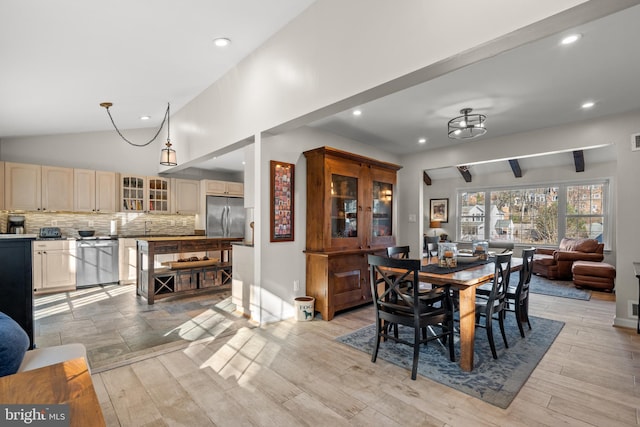 dining room with lofted ceiling, sink, and light wood-type flooring