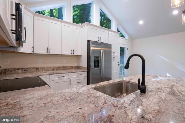 kitchen featuring white cabinetry, stainless steel fridge, sink, and light stone counters