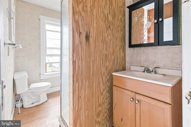 bathroom with hardwood / wood-style floors, vanity, tile walls, and toilet