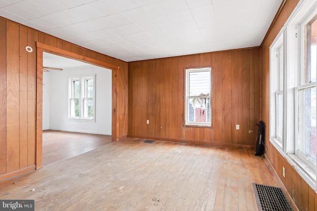 unfurnished room with wood walls and light hardwood / wood-style flooring