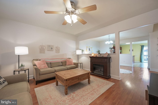 living room with wood-type flooring and ceiling fan with notable chandelier