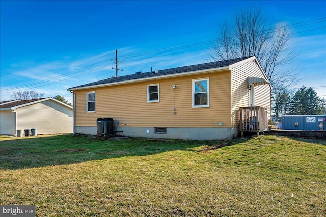 rear view of house with central AC and a lawn