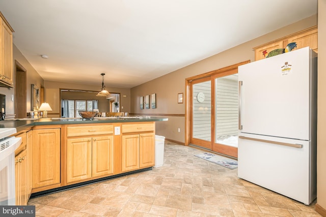 kitchen with stove, decorative light fixtures, kitchen peninsula, and white refrigerator