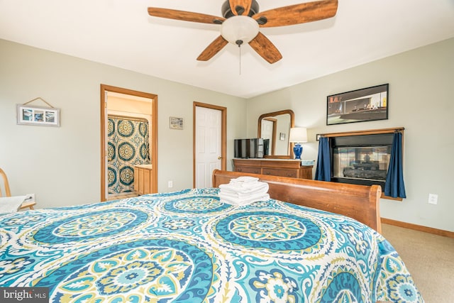 bedroom featuring a multi sided fireplace, carpet, and ceiling fan