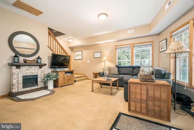 carpeted living room with a stone fireplace