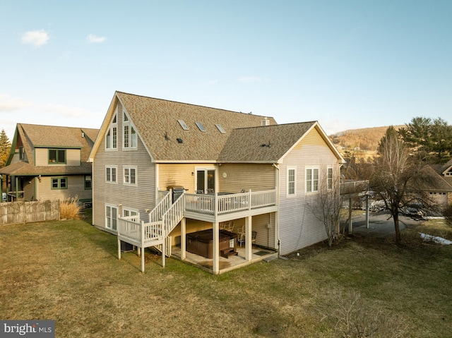 back of property with a hot tub, a wooden deck, a yard, and a patio area