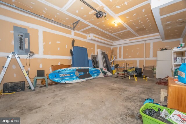 garage featuring a garage door opener, electric panel, and white refrigerator