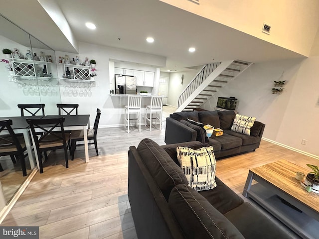 living room featuring recessed lighting, visible vents, baseboards, light wood-style floors, and stairway