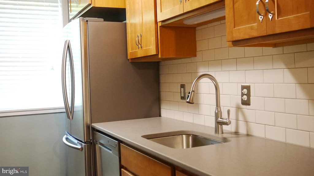 kitchen with stainless steel dishwasher, sink, and decorative backsplash