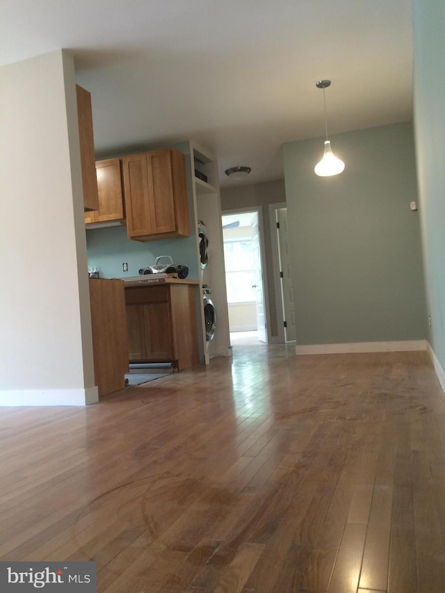 kitchen with stacked washer / drying machine, hanging light fixtures, and dark hardwood / wood-style floors