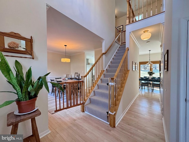 stairway featuring ornamental molding, a towering ceiling, and hardwood / wood-style floors