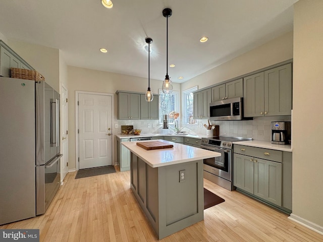 kitchen featuring light hardwood / wood-style flooring, appliances with stainless steel finishes, a center island, tasteful backsplash, and decorative light fixtures