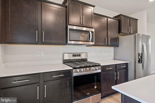 kitchen featuring dark brown cabinetry, light wood-type flooring, and appliances with stainless steel finishes