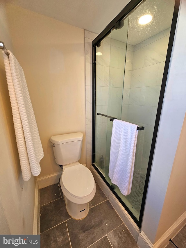 bathroom featuring tile patterned flooring, an enclosed shower, and toilet