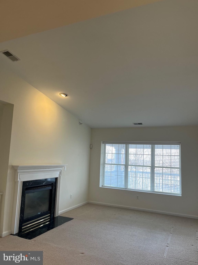 unfurnished living room featuring a fireplace, vaulted ceiling, and light carpet